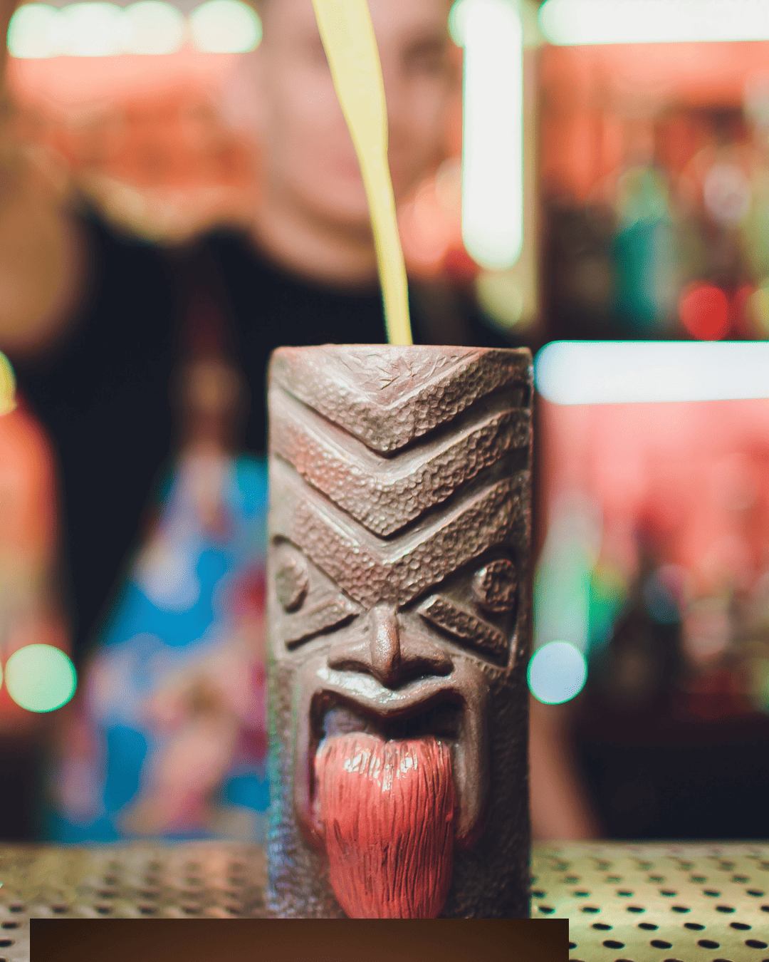 Mug à cocktail façon tiki en céramique sculptée avec langue rouge mise en avant au comptoir d'un bar